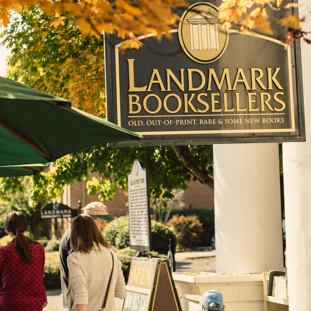 Landmark Booksellers Ila Bridal Storefront sign reads 'Landmark Booksellers' with autumn leaves and customers nearby outside a bookstore.